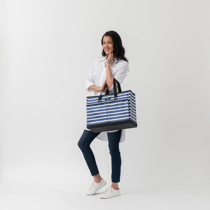 Woman holding a blue and white striped tote bag on a white background