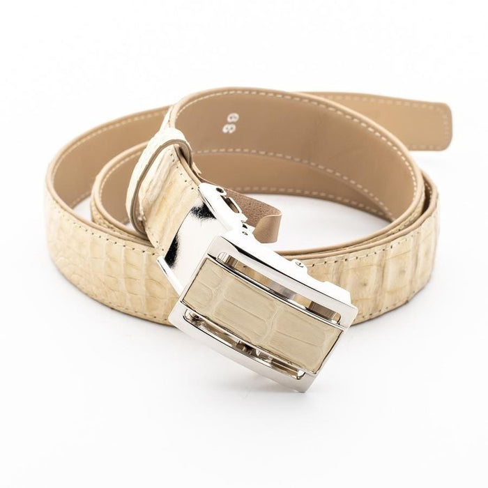 Overhead shot of the coiled ivory crocodile belt, with the silver and leather inlay buckle resting in the foreground.