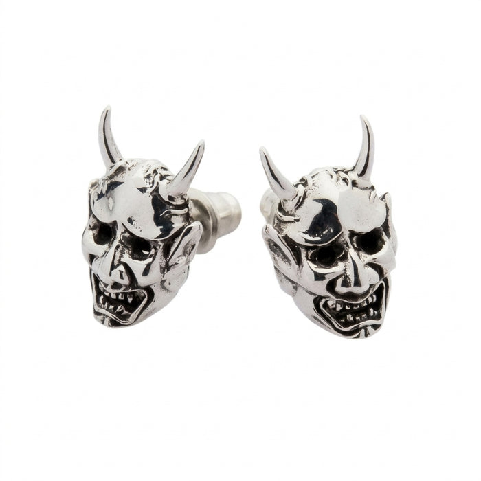 Angled perspective of the sculpted silver demon earrings revealing deep-set eyes, snarling teeth, and the back stud post.