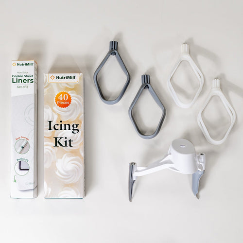 NutriMill bakers bundle including: cookie sheet liners, icing kit, pro line cookie paddles, cake paddles, and bowl scraper on grey background