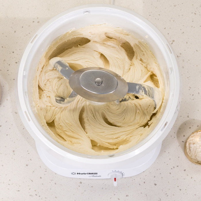 NutriMill Artiste mixing white dough with pro line cookie paddles and metal whip drive on white speckled counter