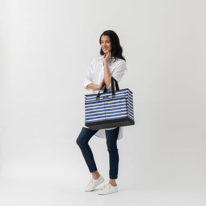 Woman holding a blue and white striped tote bag on a white background