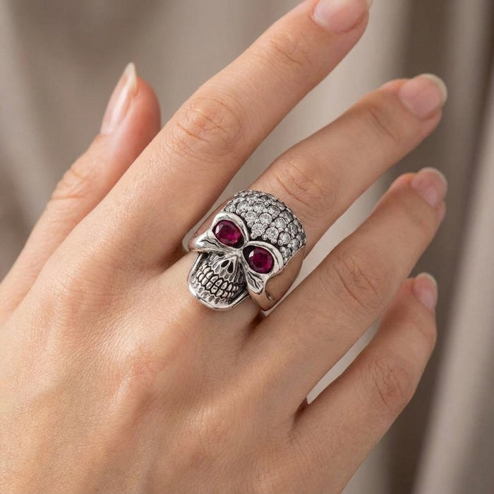 Woman wearing a sterling silver bling skull ring paved with clear CZ stones on her finger, displaying gothic biker jewelry style