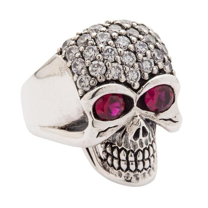 A stunning iced-out skull ring featuring dozens of clear, brilliant CZ stones and two large red eye stones for a dramatic look.