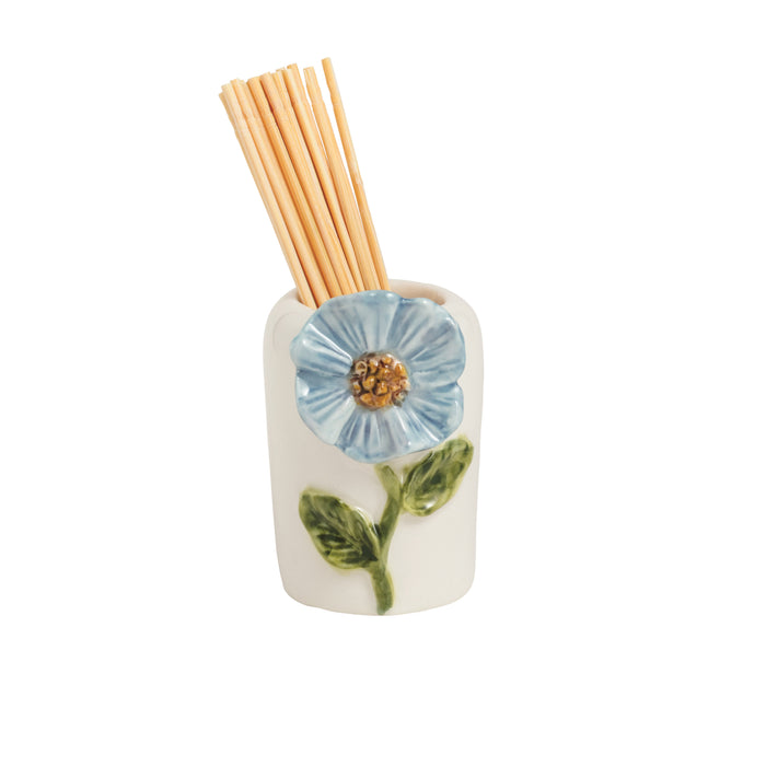 Ceramic diffuser with floral design and wooden sticks on a white background