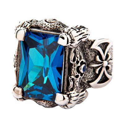 A massive sterling silver dragon claw ring, with four detailed claws holding a large, emerald-cut blue topaz stone.