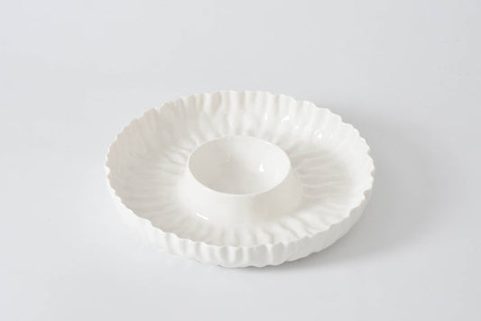 White ceramic dish with decorative rim on a light gray background