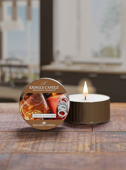 Kingle Candle Cognac & Leather daytime candle on a wooden surface with a blurred background