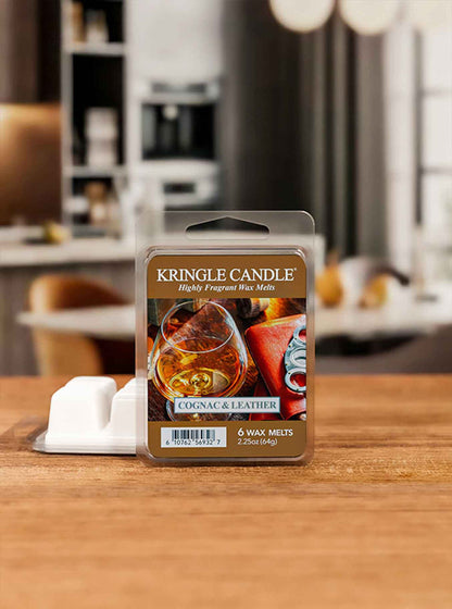 Kringle Candle Cognac & Leather wax melt package on a wooden surface with a blurred background