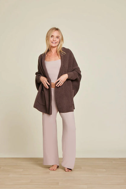A model wearing a brown CozyChic Blanket Wrap with ribbed cuffs and front patch pockets, paired with a beige tank top and matching pants.