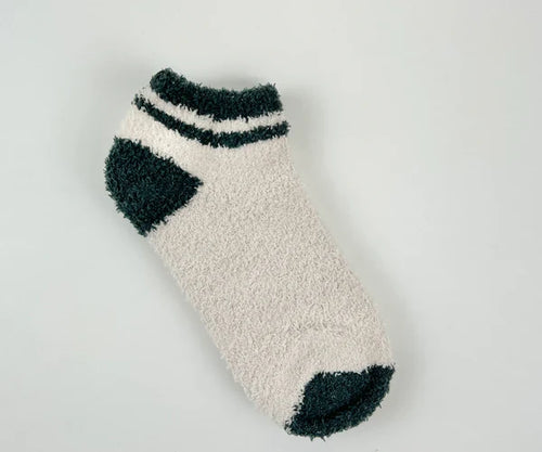 Fluffy white sock with dark green accents on a light gray background