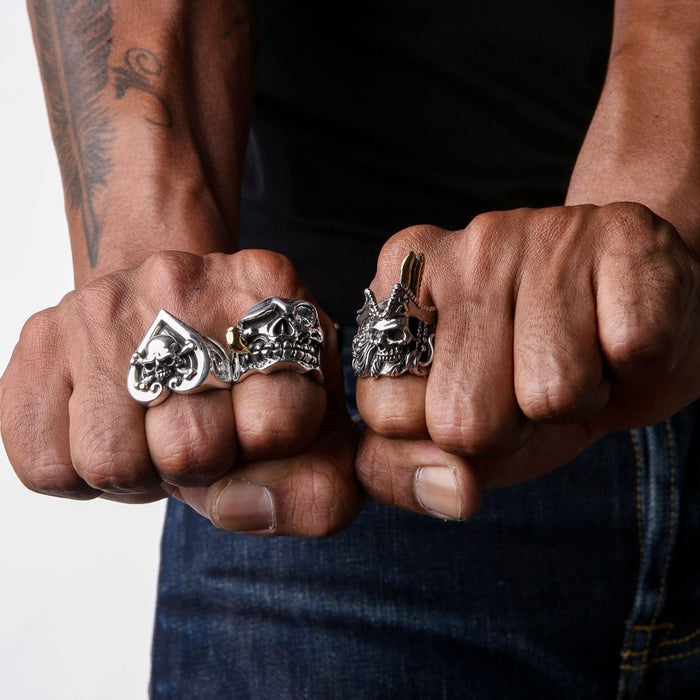 Two fists wearing heavy silver biker rings including the ace skull design