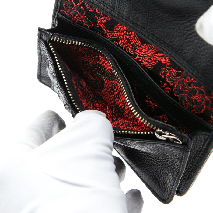 The interior of a black leather wallet showing the hidden and luxurious red emperor dragon silk lining in the zip pocket.