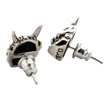 The men's green eye devil earrings displayed on a black surface to make the polished silver and green gems pop.