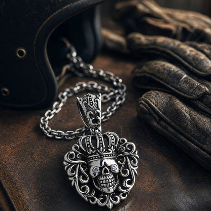 Resting on weathered leather beside a helmet and riding gloves, chain coiled behind the crowned skull pendant