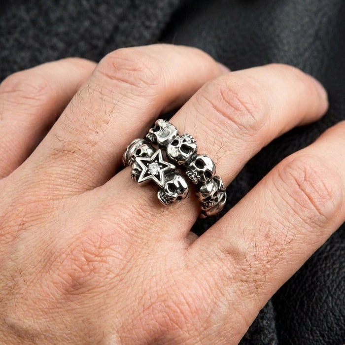 Close-up of a hand modeling the heavy .925 silver band, highlighting the wrap-around skull design and jeweled star motif.
