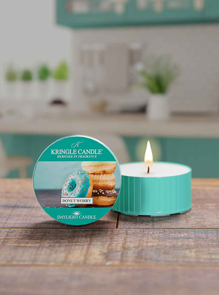 Kingle Candle 'Donut Worry' daylight candle on a wooden surface with a kitchen background.