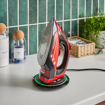 Red and black iron on a white surface with a green tiled wall in the background