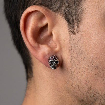 Worn on a man's ear, the 9mm x 14mm sterling silver skull stud shows its garnet pavé crown at real scale