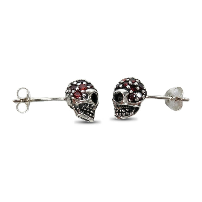 Side profile of the oxidized silver skull studs showing hollow eye sockets and the dotted teeth grid