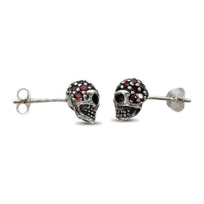Side profile of the oxidized silver skull studs showing hollow eye sockets and the dotted teeth grid