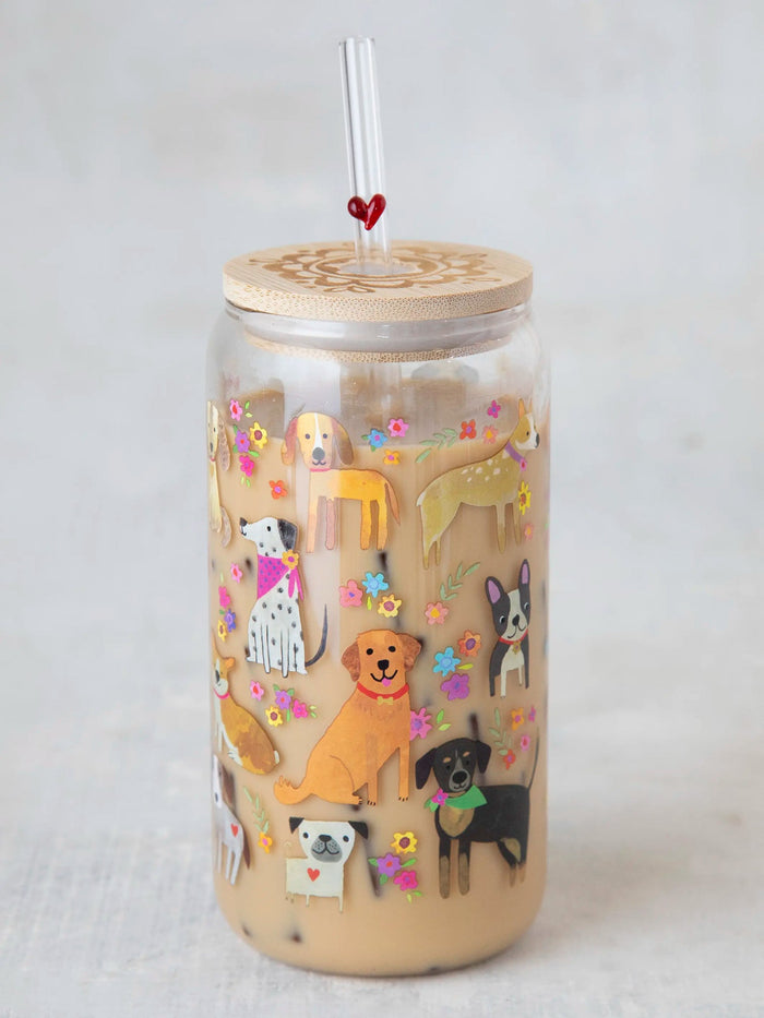 A clear glass tumbler with a dog-themed design, including various illustrated dogs and a bamboo lid, accompanied by a glass straw with a heart decoration on the top.