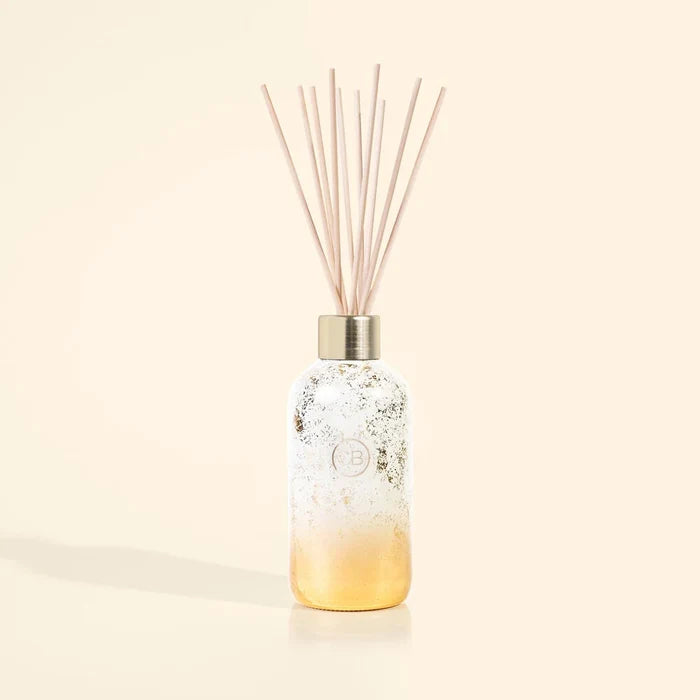 a gold shimmer capri blue reed diffuser displayed against a beige background