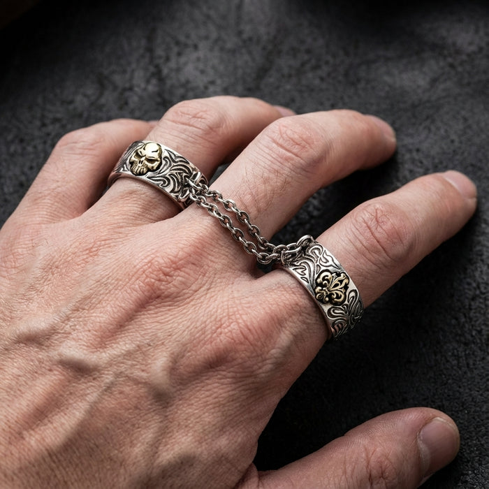 Close-up of a white male hand wearing a goth chained two-finger ring featuring soft studio lighting and a punk-style editorial aesthetic.