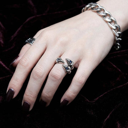Woman wearing gothic dragon claw ring with blue stones on middle finger against velvet background