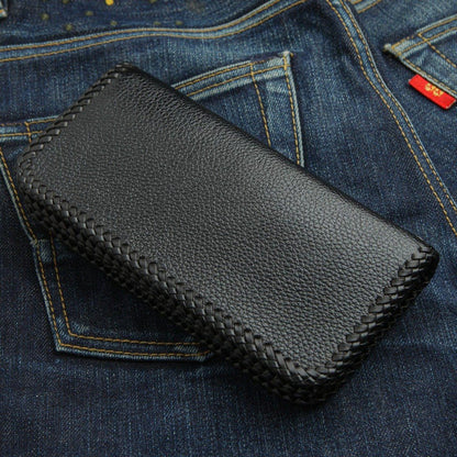 Reverse side of the black pebbled leather wallet lying on denim, emphasizing the continuous braided edge stitching.