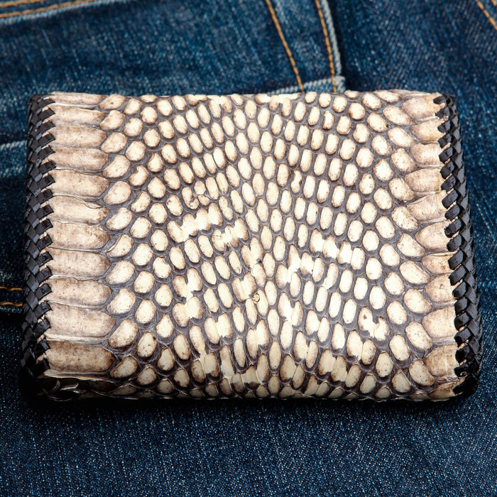 Large natural snake scales in cream and dark brown, framed by braided lacing, viewed straight down.