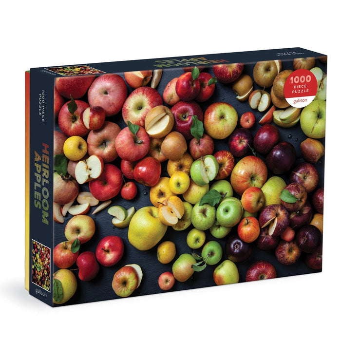 A 1000 piece puzzle box featuring a vibrant image of various heirloom apples on a dark background. The box is labeled with 'Heirloom Apples' and indicates '1000 pieces' and 'Random cut'.