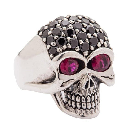 A gothic-style crystal skull ring with fiery red eyes and a sparkling black pavé forehead, handcrafted in sterling silver.