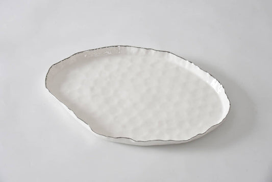 Decorative ceramic plate with textured edge on a light gray background