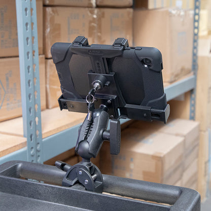 A rugged tablet is securely held in a LockVise™ Locking Tablet Clamp Mount with 38mm Ball Compatibility, which is attached to a rolling cart, with cardboard boxes stacked on metal shelves in the background.