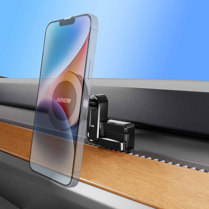 A transparent smartphone is mounted on a black and silver clamp attached to the edge of a wood and metal surface, set against a blue gradient background—an ideal setup for showcasing the Magnetic Phone Vent Mount for Tesla Model 3 (2017–2022) & Model Y (2020–2023), a must-have accessory that features a secure magnetic vent mount.