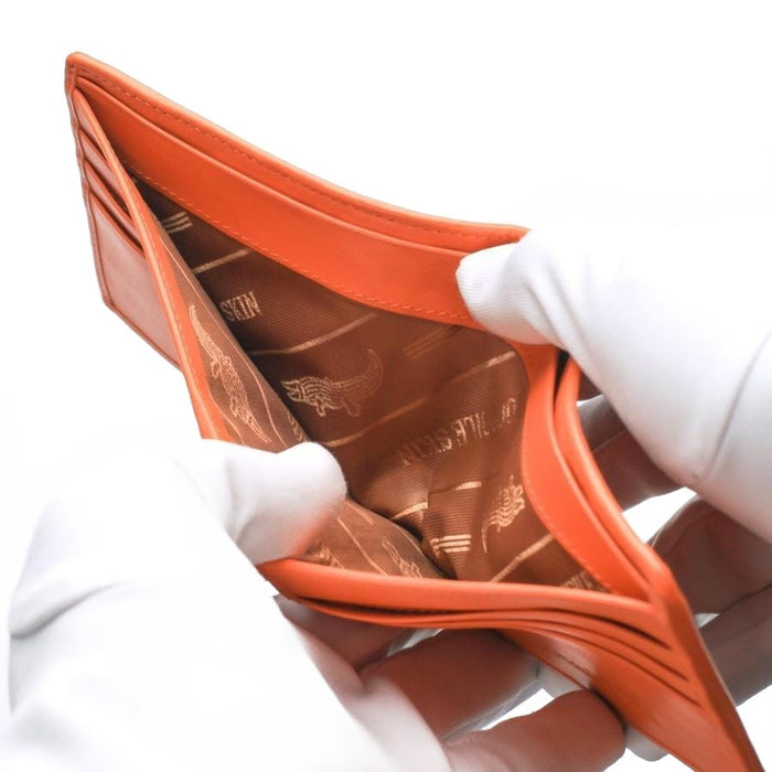 Gloved hands holding open the bill compartment of the orange crocodile wallet, revealing the premium fabric lining with a crocodile logo.