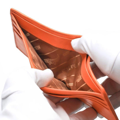 Gloved hands holding open the bill compartment of the orange crocodile wallet, revealing the premium fabric lining with a crocodile logo.