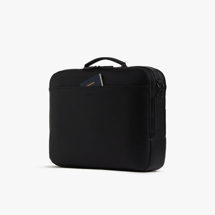 Carbon Black (Vegan Leather) | Angled view of the Metro Briefcase in Carbon Black, highlighting the front pocket with a passport partially tucked inside