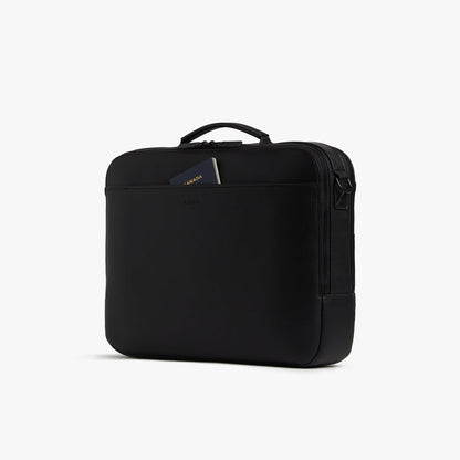 Carbon Black (Vegan Leather) | Angled view of the Metro Briefcase in Carbon Black, highlighting the front pocket with a passport partially tucked inside