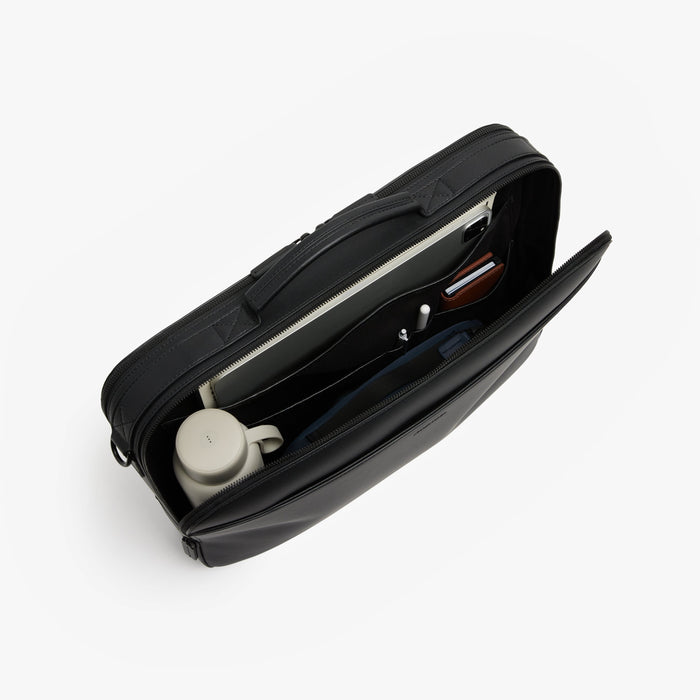 Carbon Black (Vegan Leather) | Angled view of open interior view of Metro Briefcase in Carbon Black with iPad, water bottle, pens, wallet and accessories