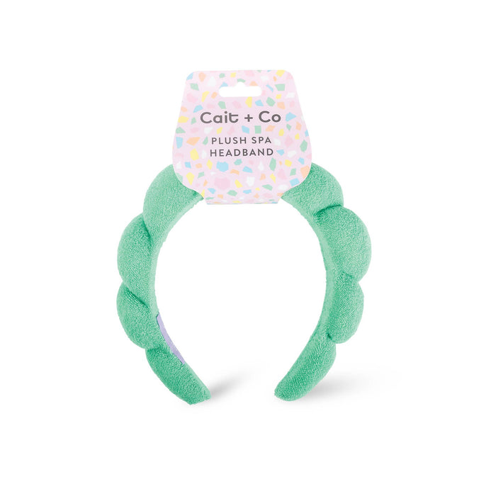 A green plush spa headband with a fluffy texture, branded with 'cait + co' on a white background.