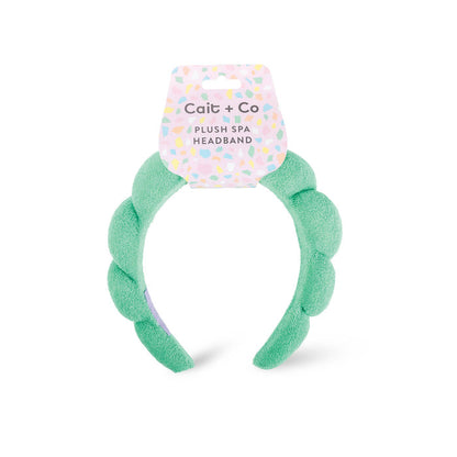 A green plush spa headband with a fluffy texture, branded with 'cait + co' on a white background.