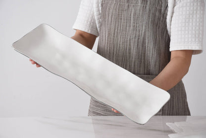 Person holding a long, thin, white object against a neutral background
