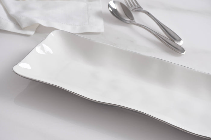 White ceramic plate on a white surface with silver cutlery.