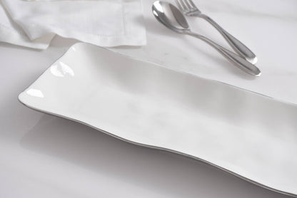 White ceramic plate on a white surface with silver cutlery.