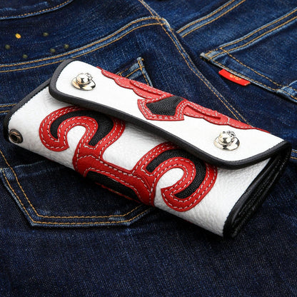 White shagreen under black and red overlays, two silver skull snaps and a pair of black eyelets in line.