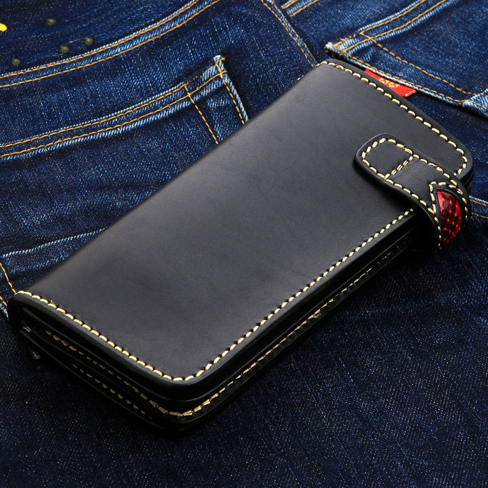 Closure strap crosses the smooth black face, pale stitching outlining it and red showing beneath.