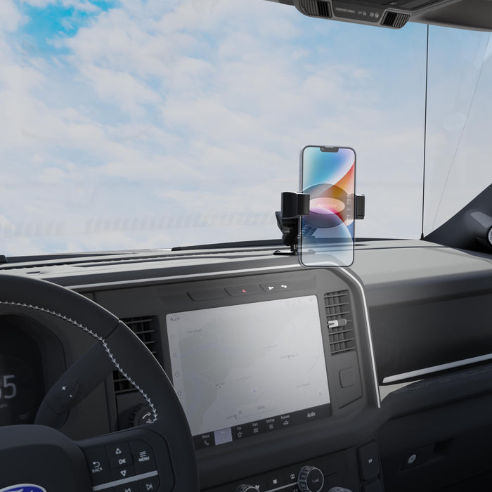 A modern vehicle’s interior features a smartphone securely mounted on the RoadVise® Ultra Pro Phone Holder 5” AMPS Drill-Base Mount, with the car’s steering wheel, expansive center display, and a clear sky visible through the windshield.