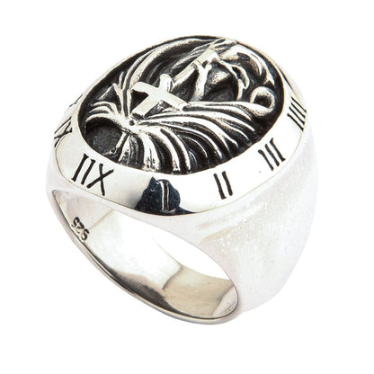A shot of the Roman numeral ring, detailing the oxidized carving of the cross, hands, and wings.